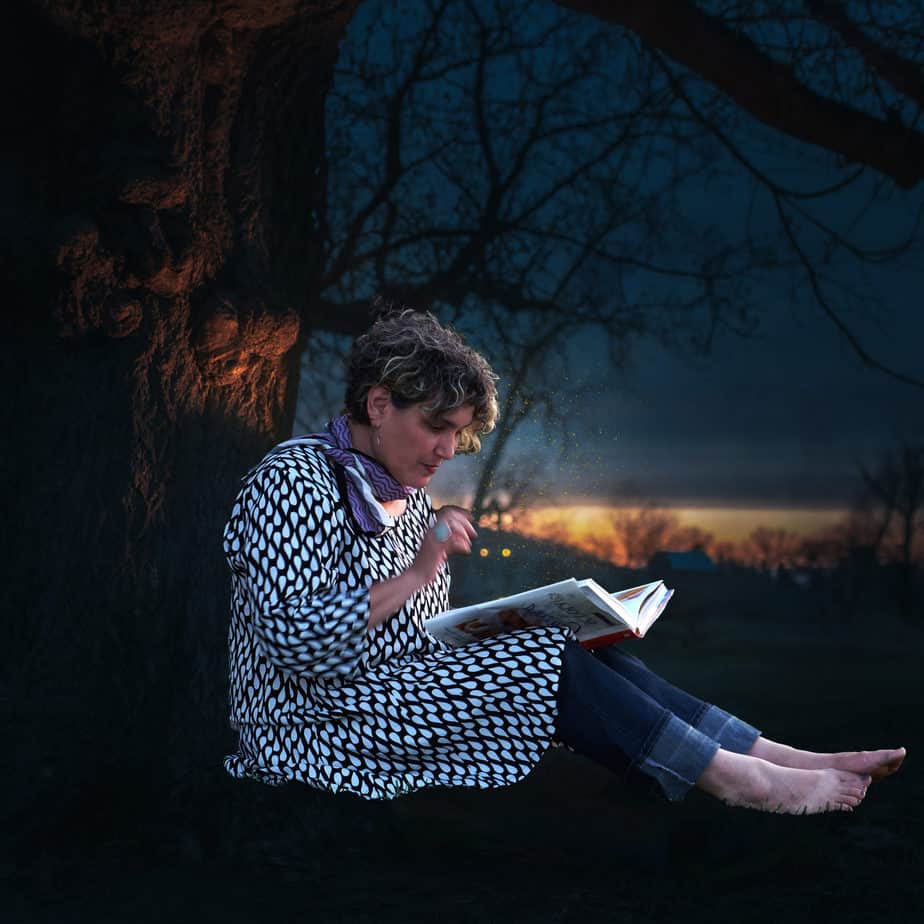 Maia reading next to a tree at night