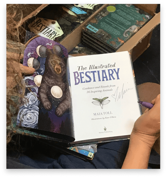 Maia signing inside of The Illustrated Bestiary