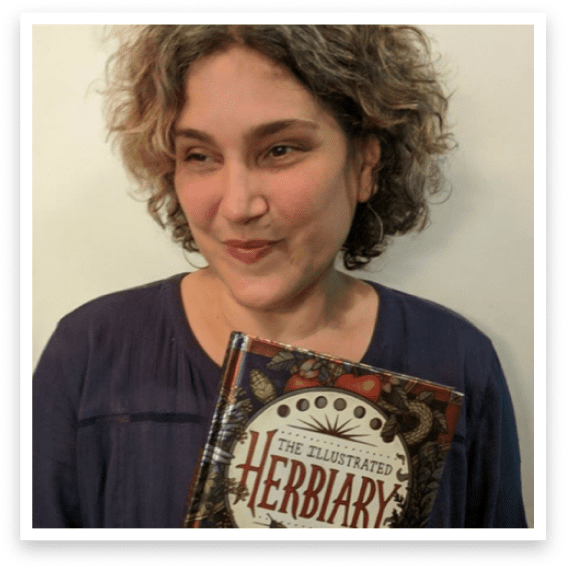 Maia holding her first published book, The Illustrated Herbiary.
